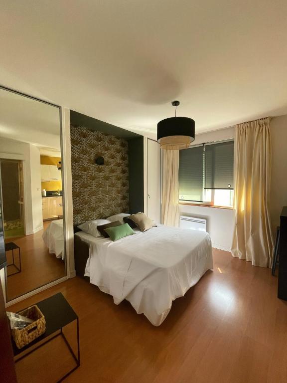 a bedroom with a large white bed and a mirror at Charmant Studio au coeur de Castanet-Tolosan in Castanet-Tolosan