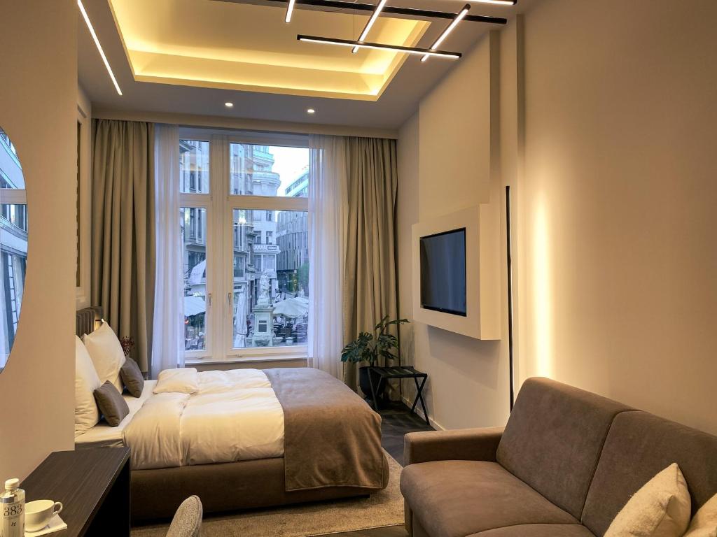 ブダペストにあるDamas Suites Budapestのベッドルーム(ベッド1台、ソファ、テレビ付)