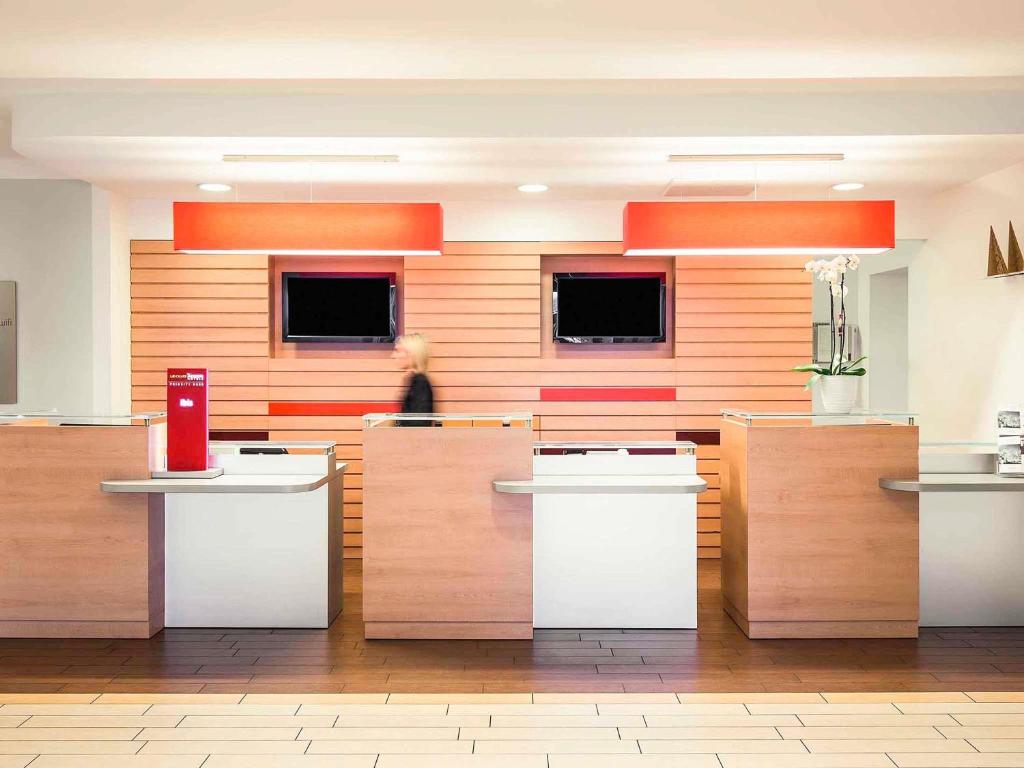 un vestíbulo con una mujer de pie en el fondo en Hotel Ibis Milano Malpensa, en Cardano al Campo
