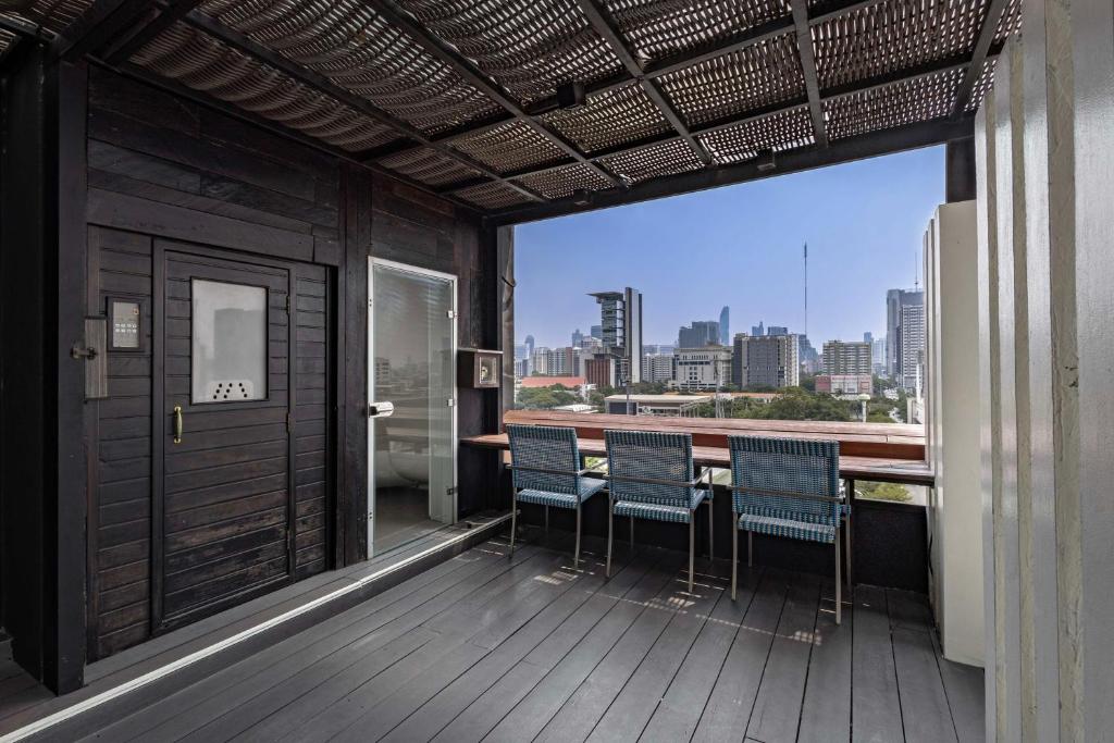 a balcony with chairs and a view of the city at Siam@Siam, Design Hotel Bangkok in Bangkok