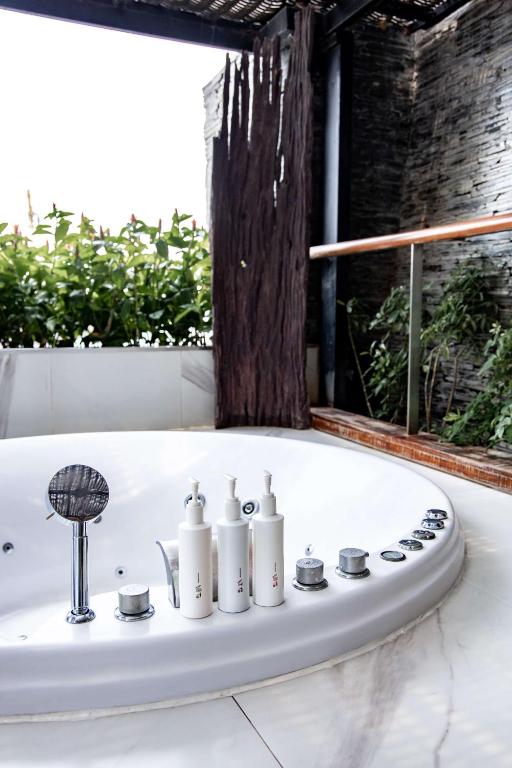 a bath tub with four white bottles on it at Siam@Siam, Design Hotel Bangkok in Bangkok