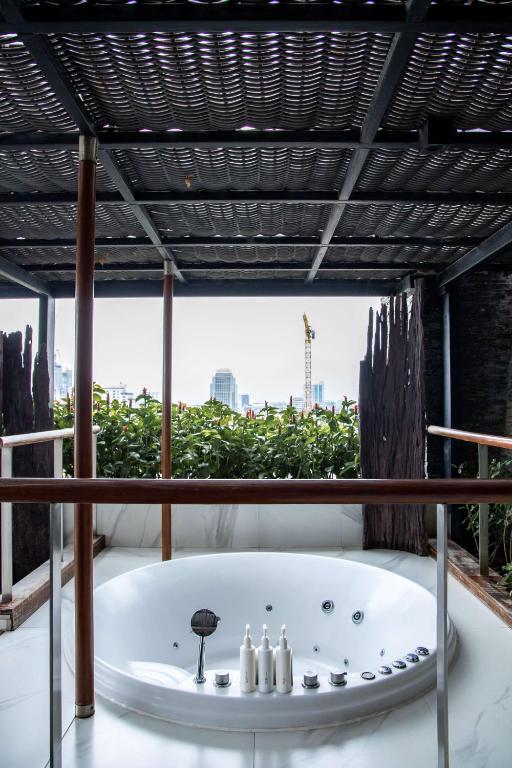 a bath tub in a room with a large window at Siam@Siam, Design Hotel Bangkok in Bangkok