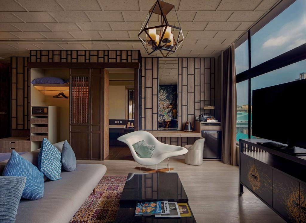 a living room with a couch and a tv at Siam@Siam, Design Hotel Bangkok in Bangkok