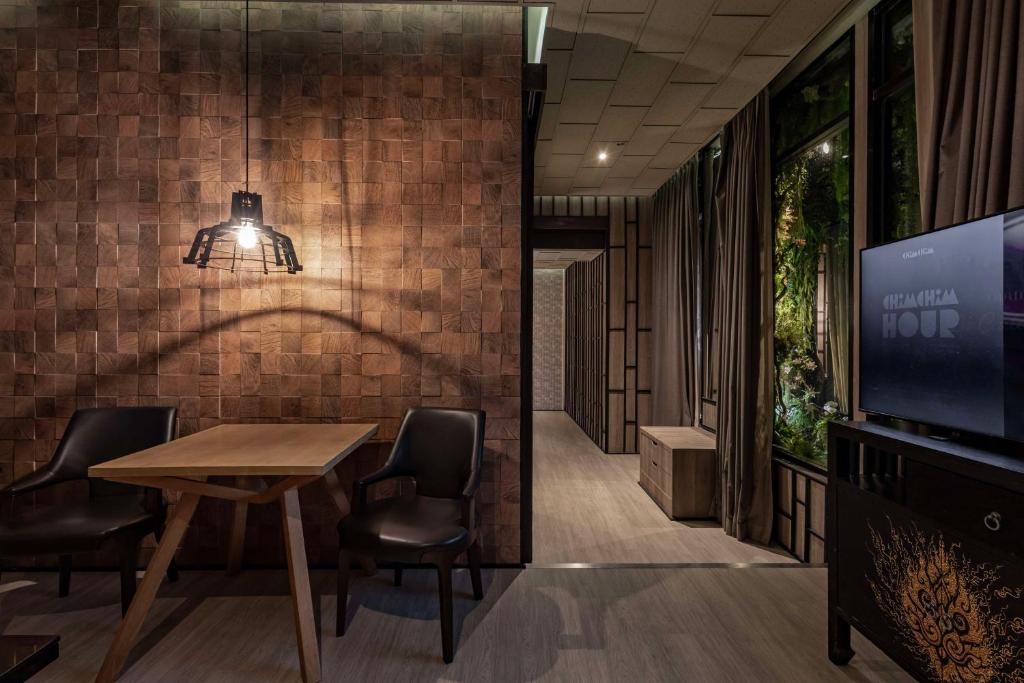 a dining room with a table and chairs and a tv at Siam@Siam, Design Hotel Bangkok in Bangkok