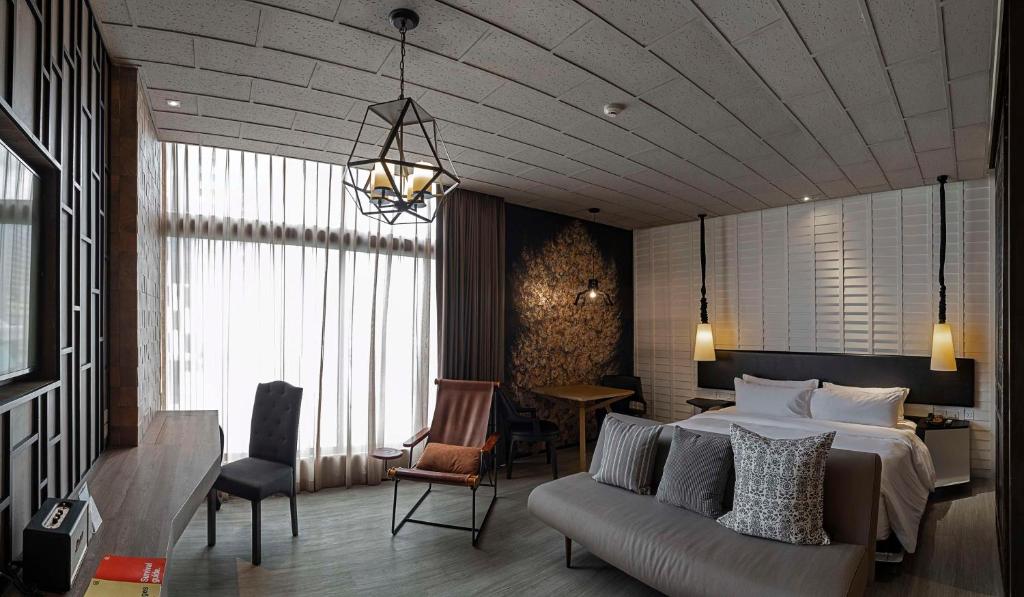 a bedroom with a bed and a couch and a table at Siam@Siam, Design Hotel Bangkok in Bangkok