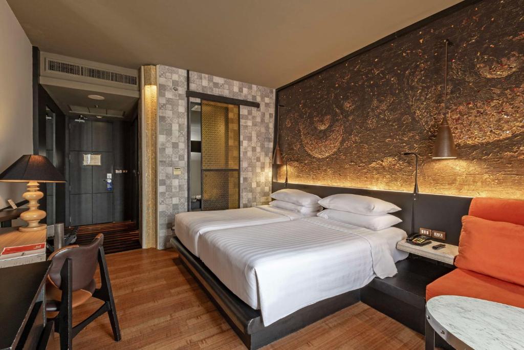 a bedroom with a large white bed and a table at Siam@Siam, Design Hotel Bangkok in Bangkok