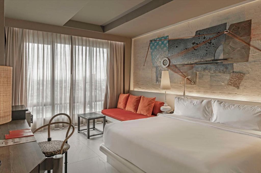a bedroom with a large white bed and a couch at Siam@Siam, Design Hotel Bangkok in Bangkok