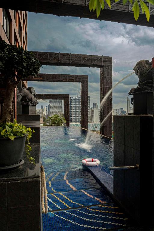 a swimming pool with a fountain in the middle of a city at Siam@Siam, Design Hotel Bangkok in Bangkok