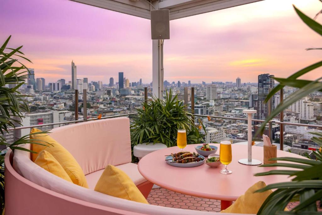 a table and chairs on a balcony with a view of a city at Siam@Siam, Design Hotel Bangkok in Bangkok