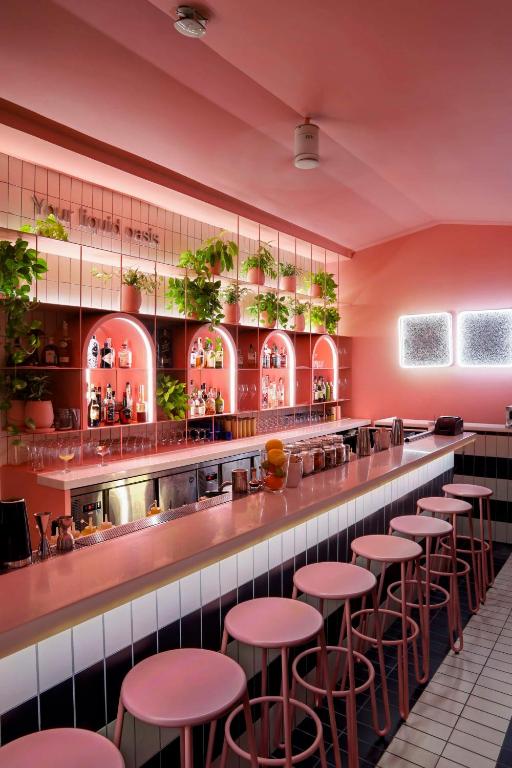 a bar in a restaurant with pink walls and stools at Siam@Siam, Design Hotel Bangkok in Bangkok