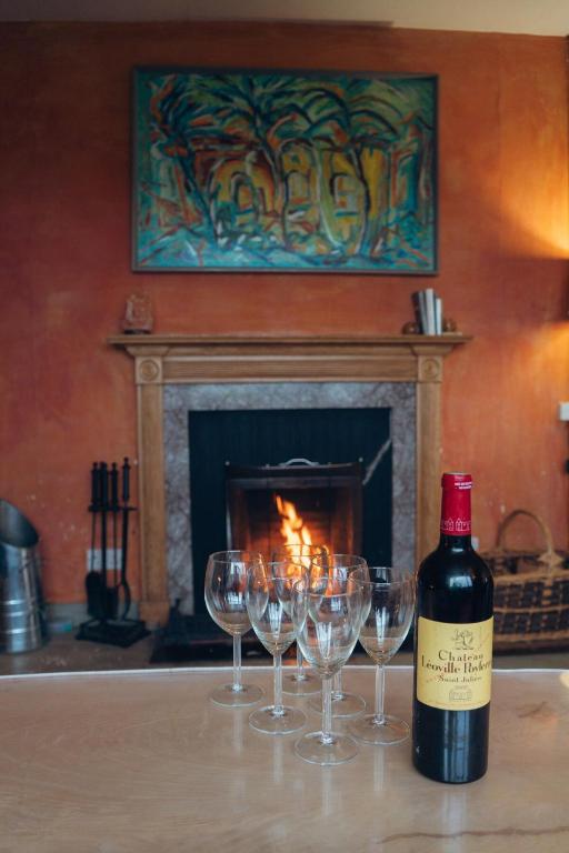 a bottle of wine sitting on a table with wine glasses at Ardtalnaig House, Loch Tay in Ardtalnaig