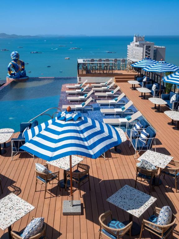 a group of tables and umbrellas next to a swimming pool at Siam At Siam Design Hotel Pattaya in Pattaya