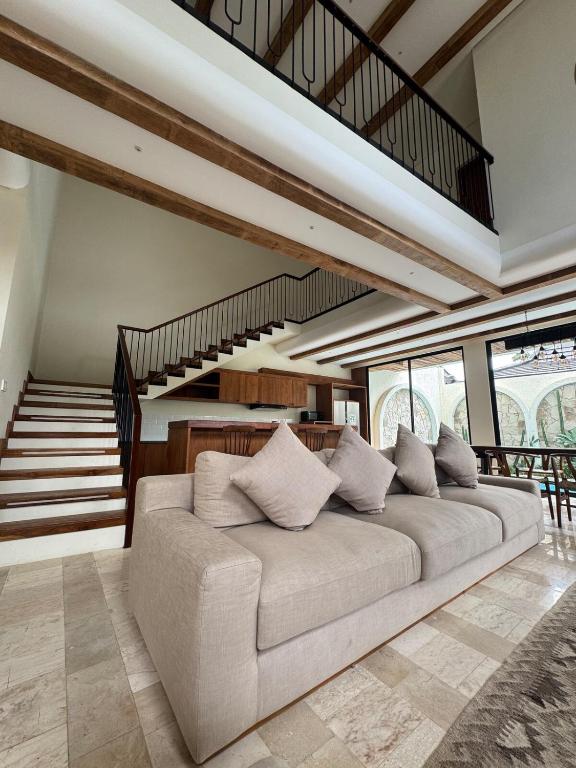 a large couch in a living room with a staircase at Tuluscoliving Villa Kuta 1, 4 Bedroom & 5 Bathroom in Ngurah Rai International Airport