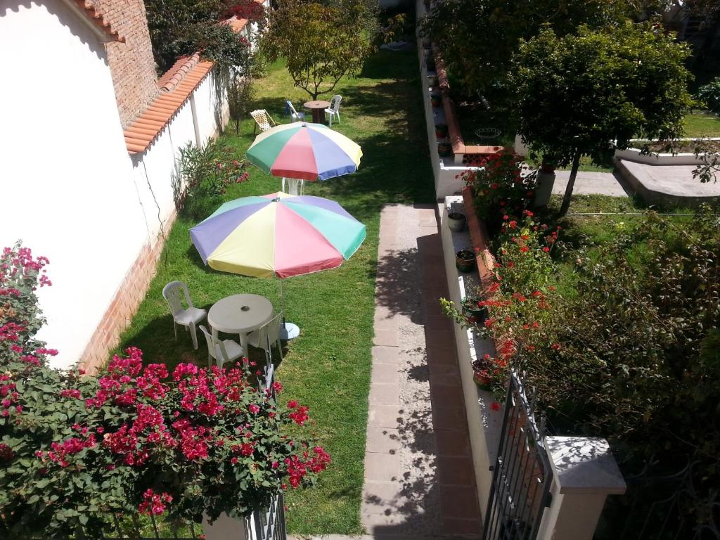 un patio con 2 sombrillas en el césped en Villa Oropeza Hostel, en Sucre