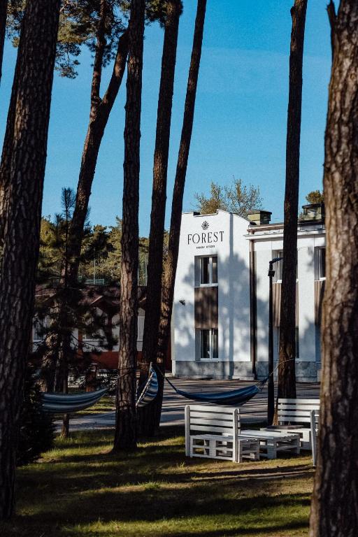 a white building with hammocks in a park with trees at FOREST Family Resort Ustka in Ustka