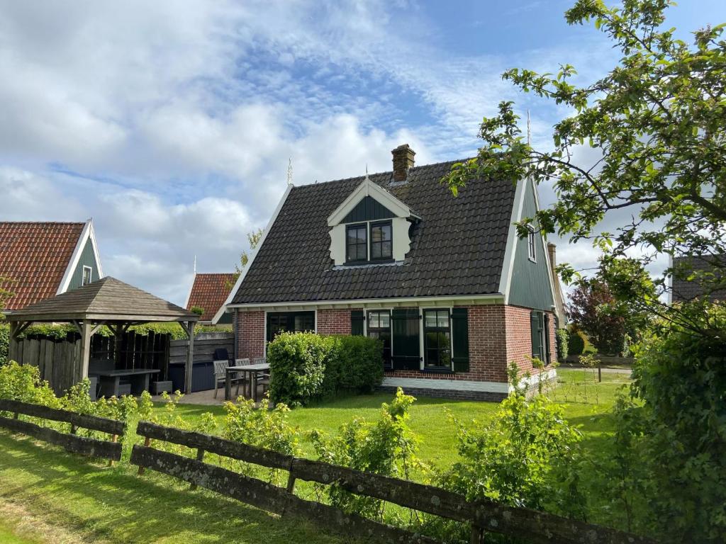 a house with a fence in the yard at Holiday Home Wiringherlant-6 by Interhome in Noordstroe