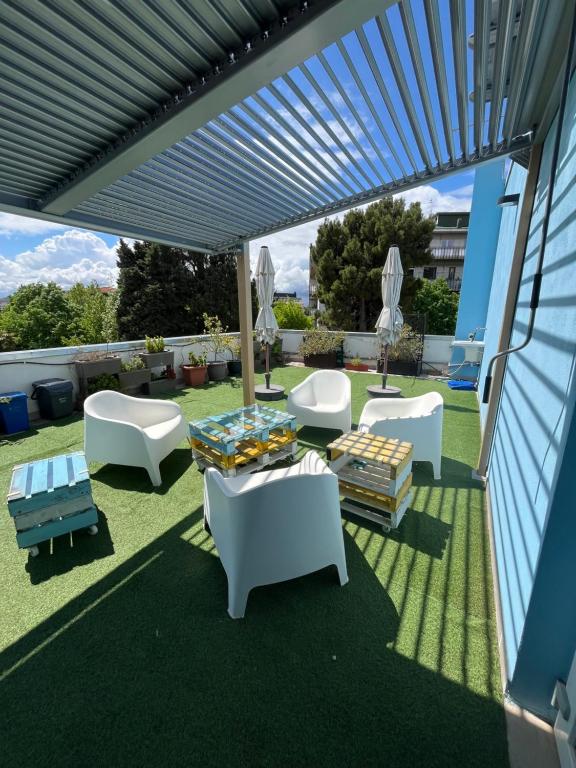 un patio con sillas blancas y mesas en el césped en B&B Il Glicine Pescara centro, en Pescara