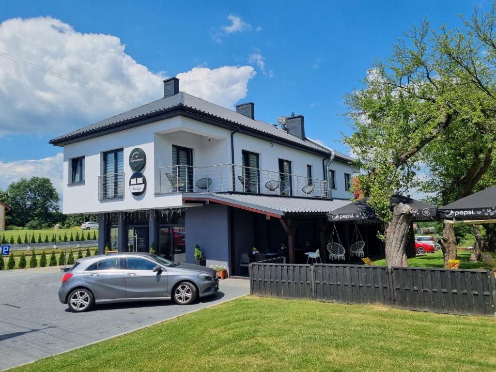 een auto geparkeerd voor een wit gebouw bij Noclegi Primavera in Jaśkowice