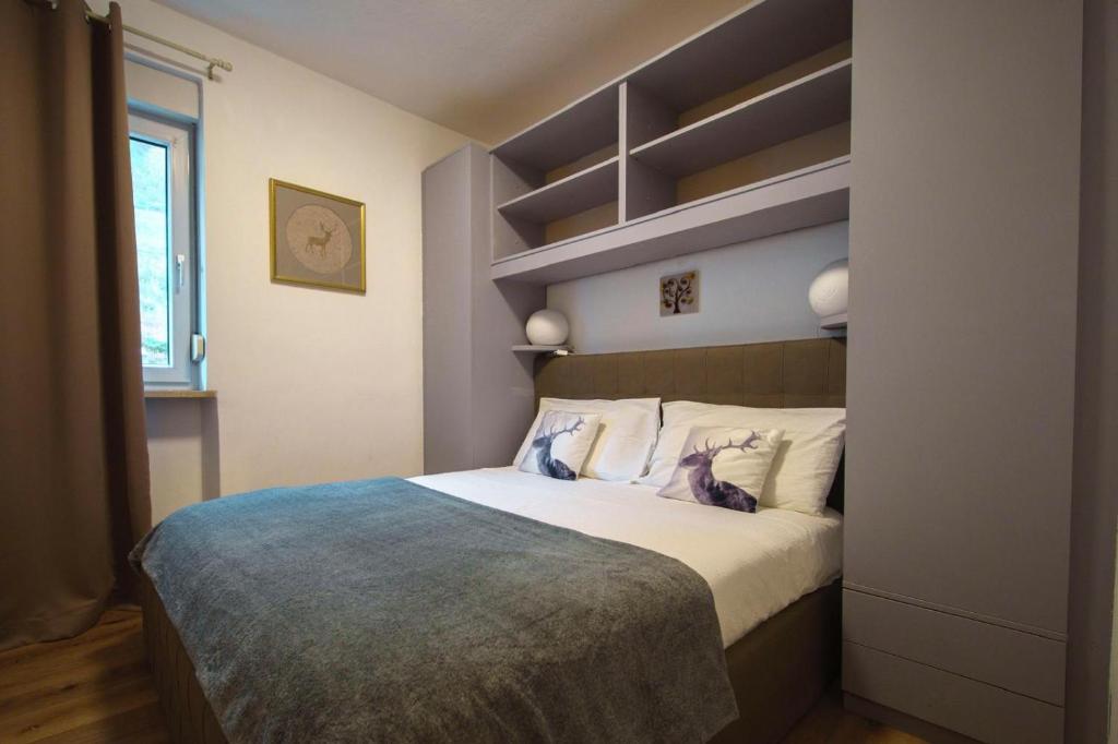 une chambre avec un grand lit avec une tête de lit dans l'établissement DOLOMIA APARTMENTS PINZOLO vicino alle funivie, à Pinzolo