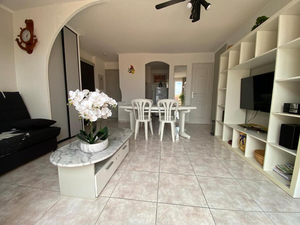 - un salon avec un canapé et une table ornée de fleurs blanches dans l'établissement Appartement 50 m de la plage vue mer, à Sainte-Marie-la-Mer