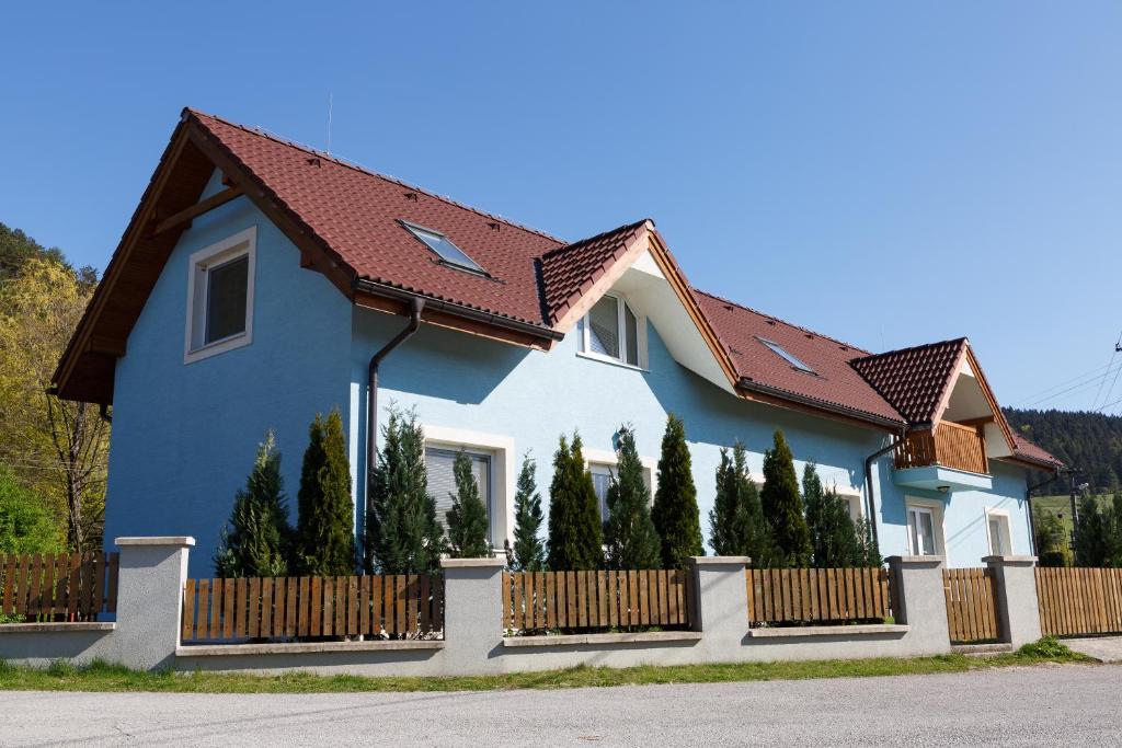Apartmánový Dom River في Blatnica: بيت ازرق به سياج واشجار