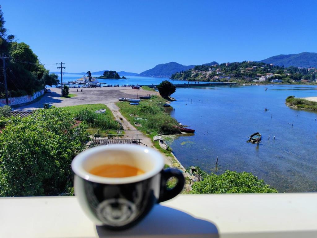 a cup of coffee sitting on a ledge overlooking a river at Anna's Apartments and Studios - Planespotter's Paradise!!! in Corfu Town