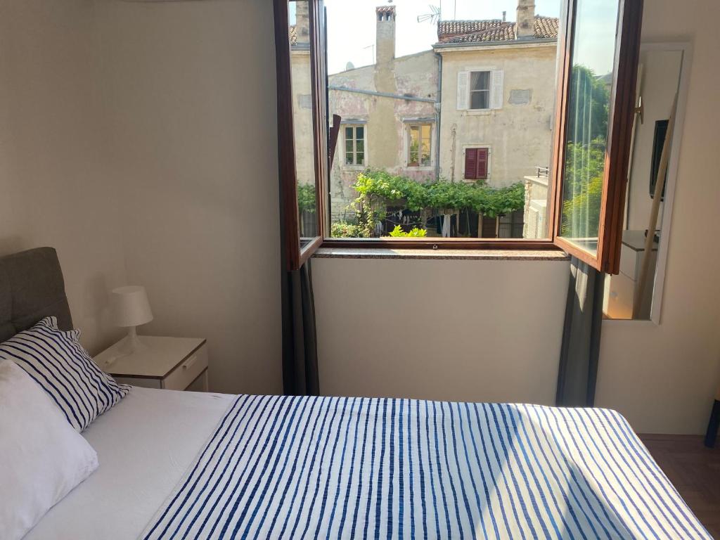 a bedroom with a bed and an open window at Guest House Marta in Rovinj