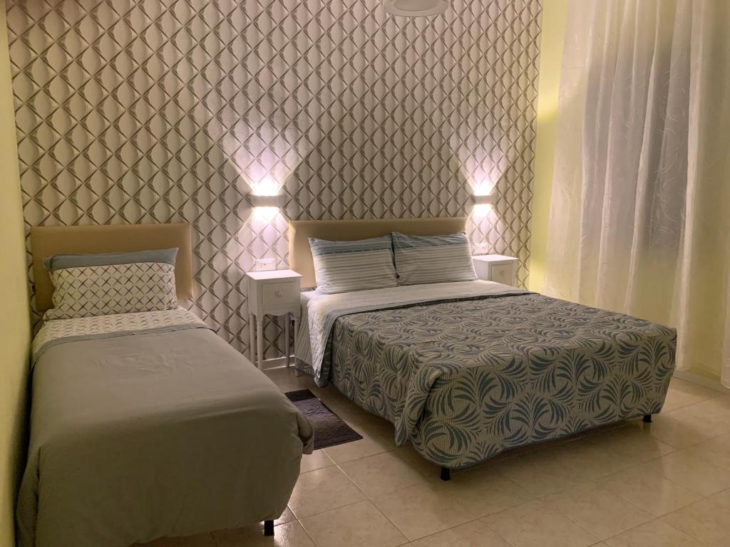 two beds in a bedroom with lights on the wall at Ca' Rosso Venice in Venice