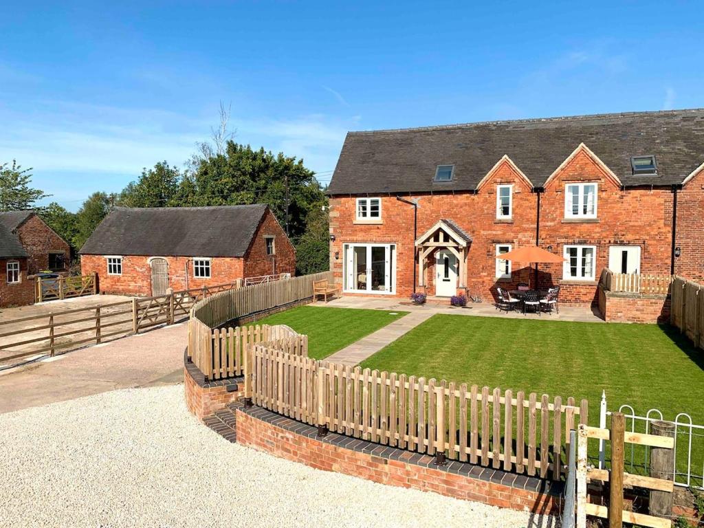 une maison en briques avec une clôture et une cour dans l'établissement Lower House Farm Cottage 1, à Ashbourne