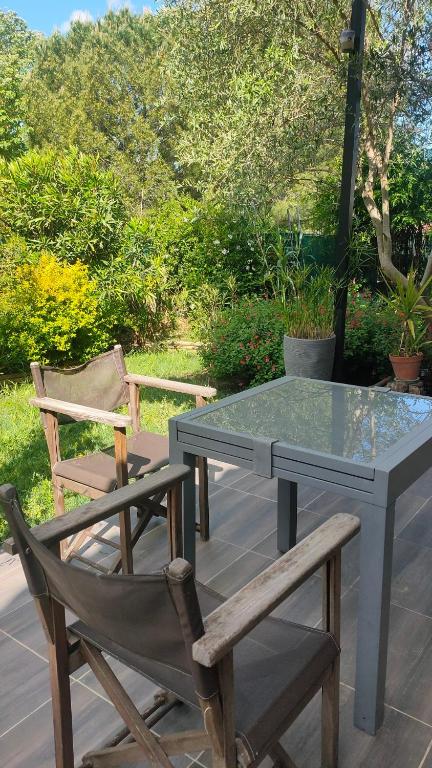 une table et deux chaises ainsi qu'une table et des chaises en verre dans l'établissement Gignac 34 Maison avec jardin 3 min du centre ville, à Gignac