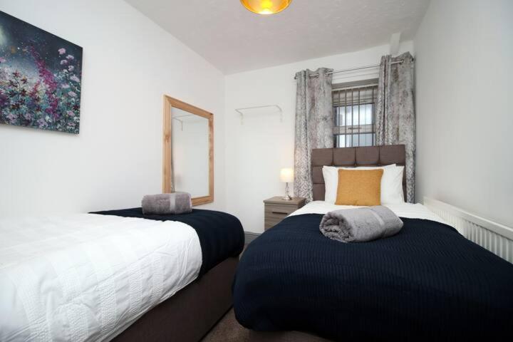 a bedroom with two beds and a mirror at City Centre, Parking, Smart Tv's in all rooms in Swansea