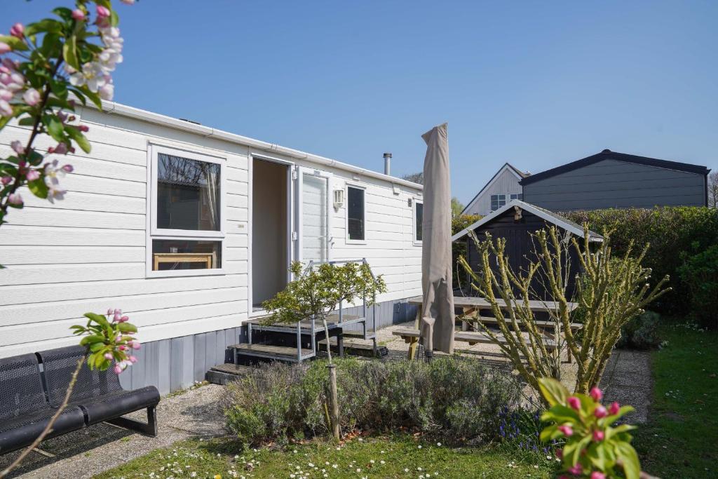 a white caravan with a porch and a house at Camping de Zandput - ZP 237 in Vrouwenpolder