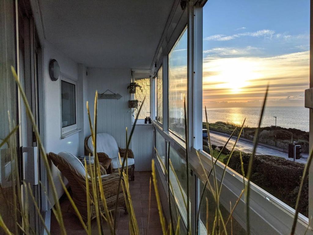 a room with a balcony with a view of the ocean at Seaview Sands Beach Apartment in Southbourne