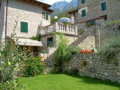 a stone building with a balcony and a yard at Ferienwohnung Mit Blick Auf Das Wasser in Sommavilla
