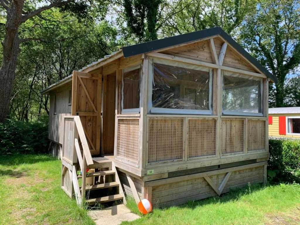 une grande maison en bois avec une échelle dans l'herbe dans l'établissement Cabane 3 étoiles - Piscine - eeedda, à Guérande