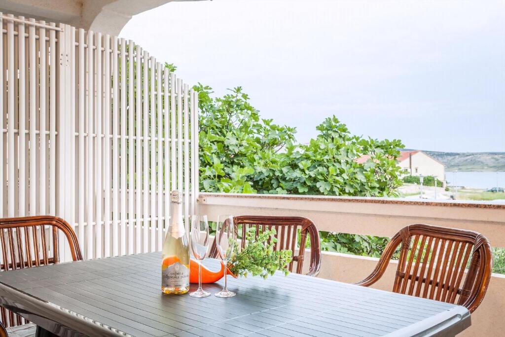 a wooden table with a bottle and glasses on a balcony at Appartement Rajka in Kustići