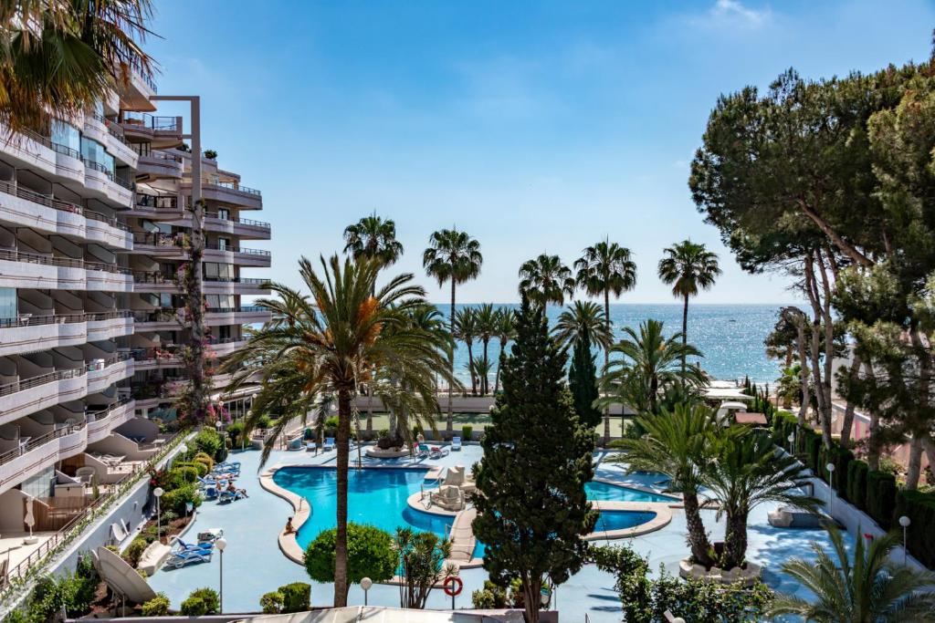 a view of the pool at a resort with palm trees and the ocean at Villas Guzman - Paraiso Mar in Calpe