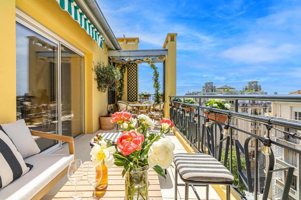 - un balcon avec un canapé et une table fleurie dans l'établissement Luxurious penthouse, 2 bedroom suites, 3 spacious terraces, gorgeous views of mountains and sea,, à Nice
