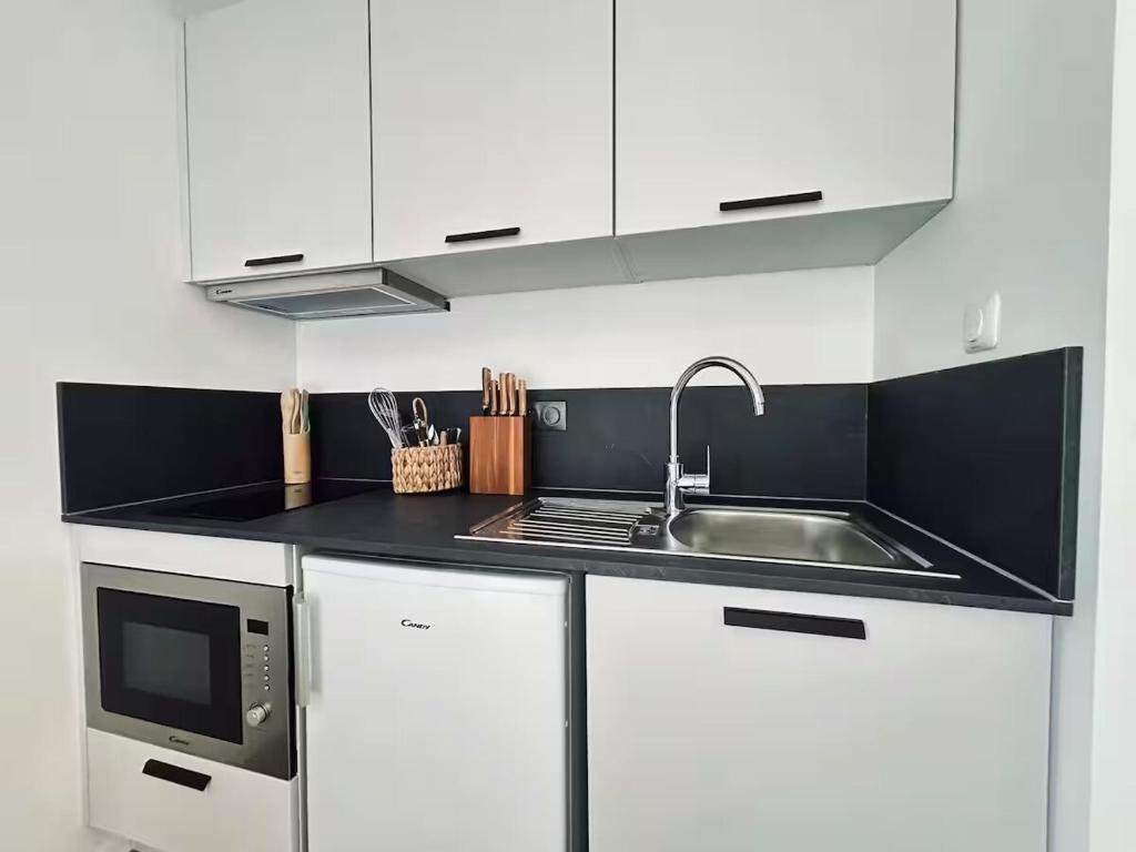 une cuisine blanche avec un évier et un micro-ondes dans l'établissement Reims résidence inn Sharies Studio confort C606, à Reims