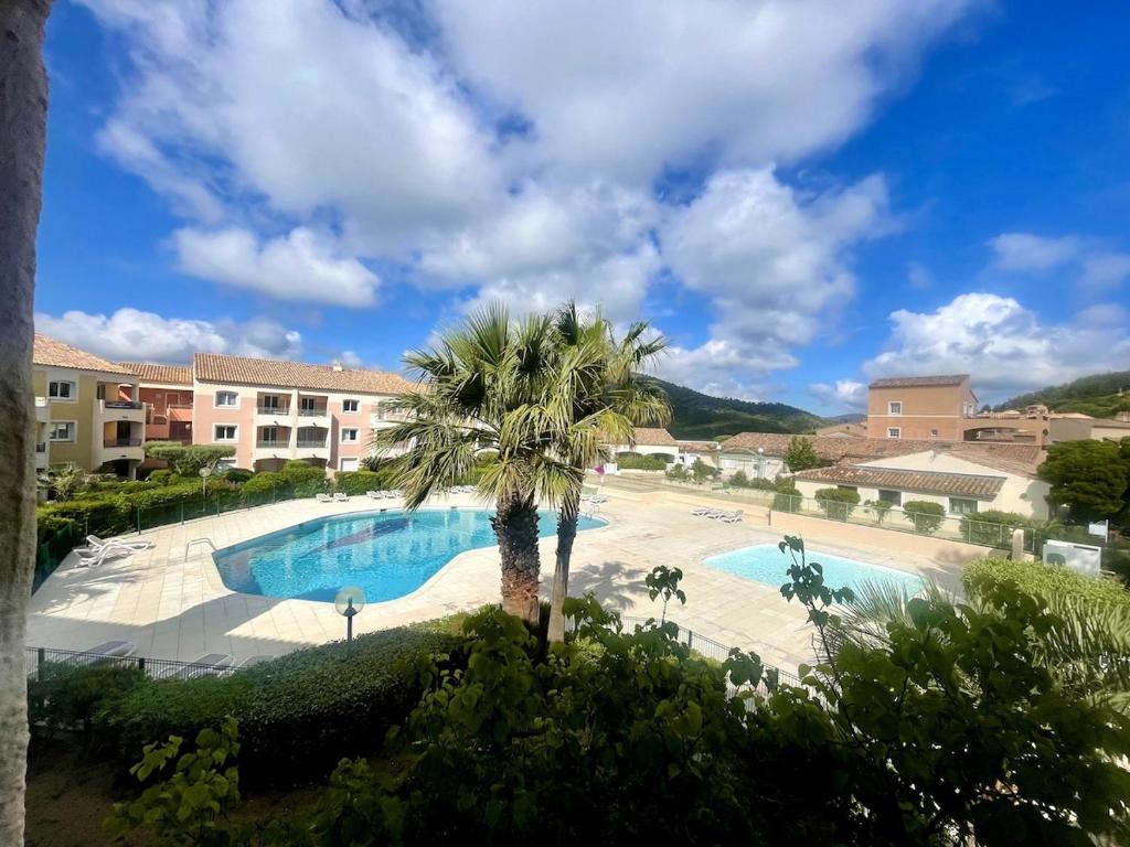 une piscine avec un palmier devant un immeuble dans l'établissement Apartment T2 cosy Les Issambres, à Roquebrune-sur Argens
