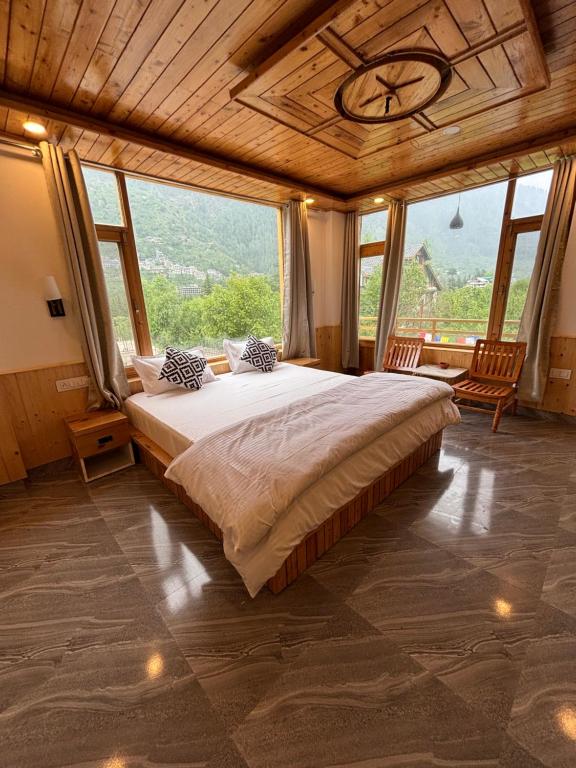 a bedroom with a large bed and large windows at deja view orchard, old manali in Manāli