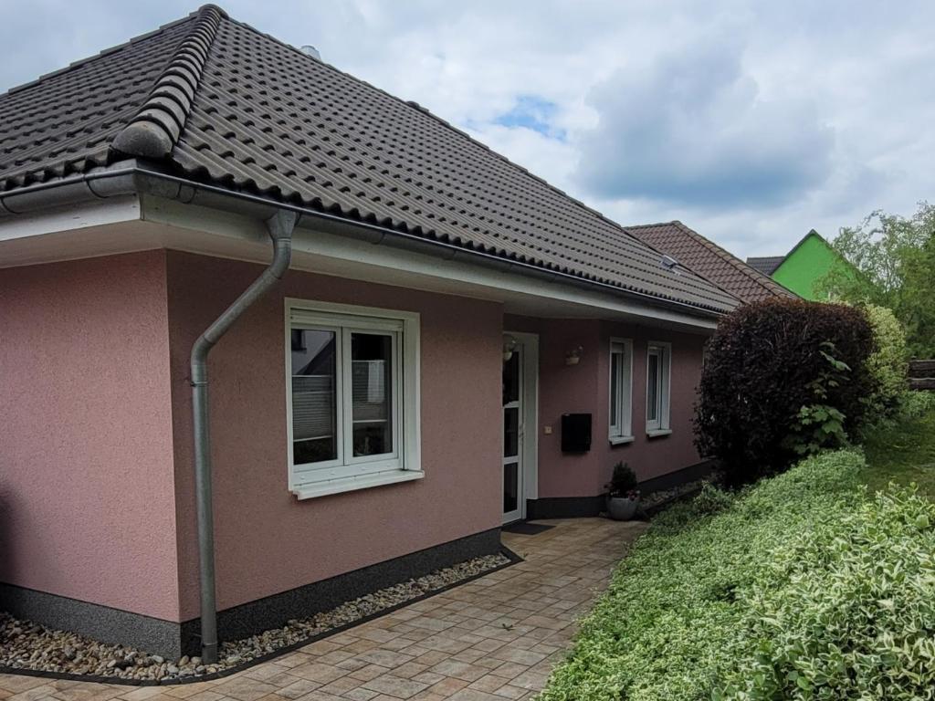 a pink house with a tile roof at Ferienhaus Fliederhain in Stollberg