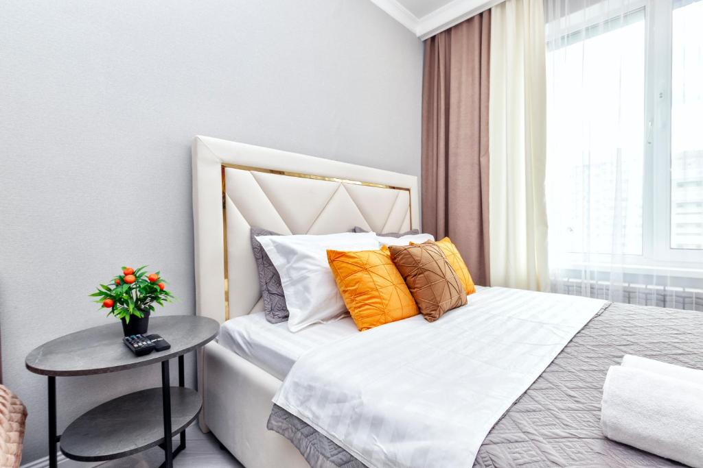 een slaapkamer met een bed met oranje en witte kussens bij Комфортные апартаменты в центре города in Astana
