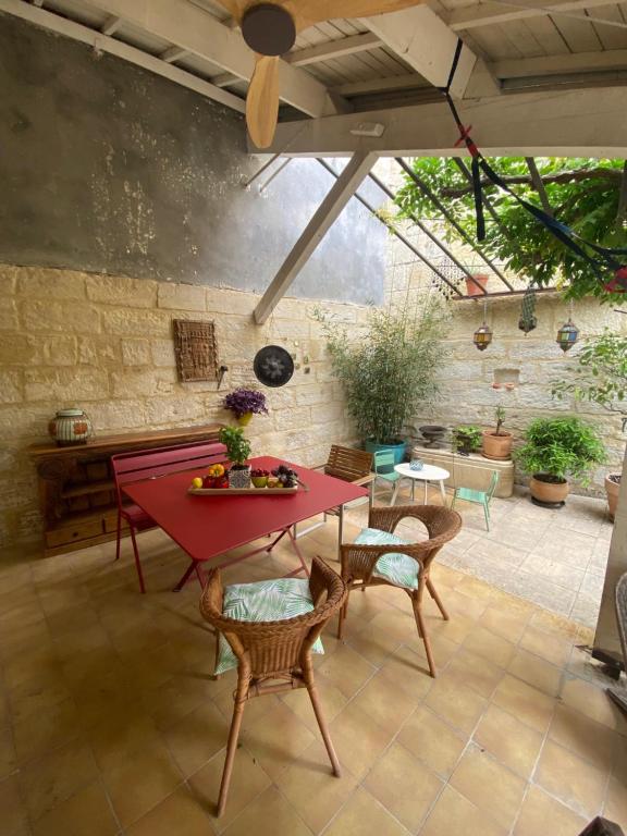 un patio avec une table et des chaises rouges dans l'établissement Charmante maison de village avec patio FOURQUES 10 minutes à pied d'Arles, à Fourques