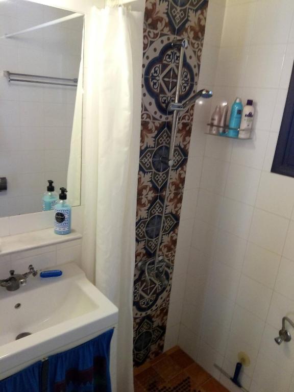 a bathroom with a sink and a shower curtain at Louloudi, charming townhouse in Skiathos