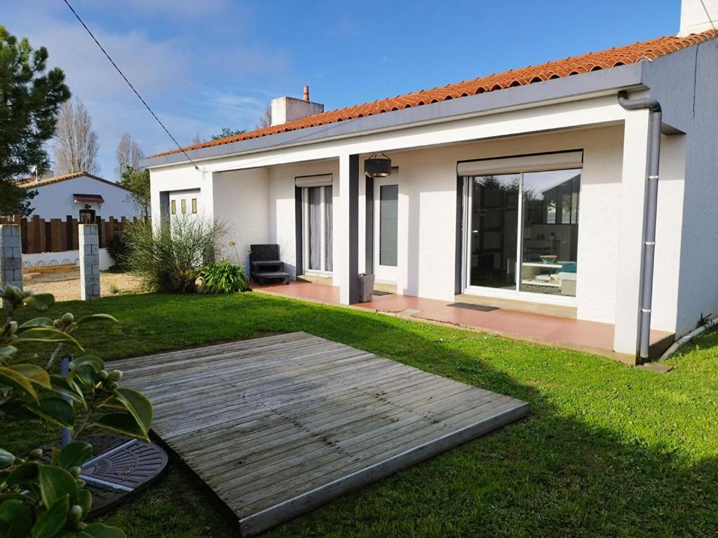 une maison avec une terrasse en bois dans la cour dans l'établissement LS0479 Maison La Gillerie, à Olonne-sur-Mer