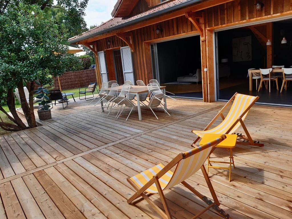 une terrasse en bois avec une table et des chaises dessus dans l'établissement Pretty House in Lège Bourg, à Lège-Cap-Ferret