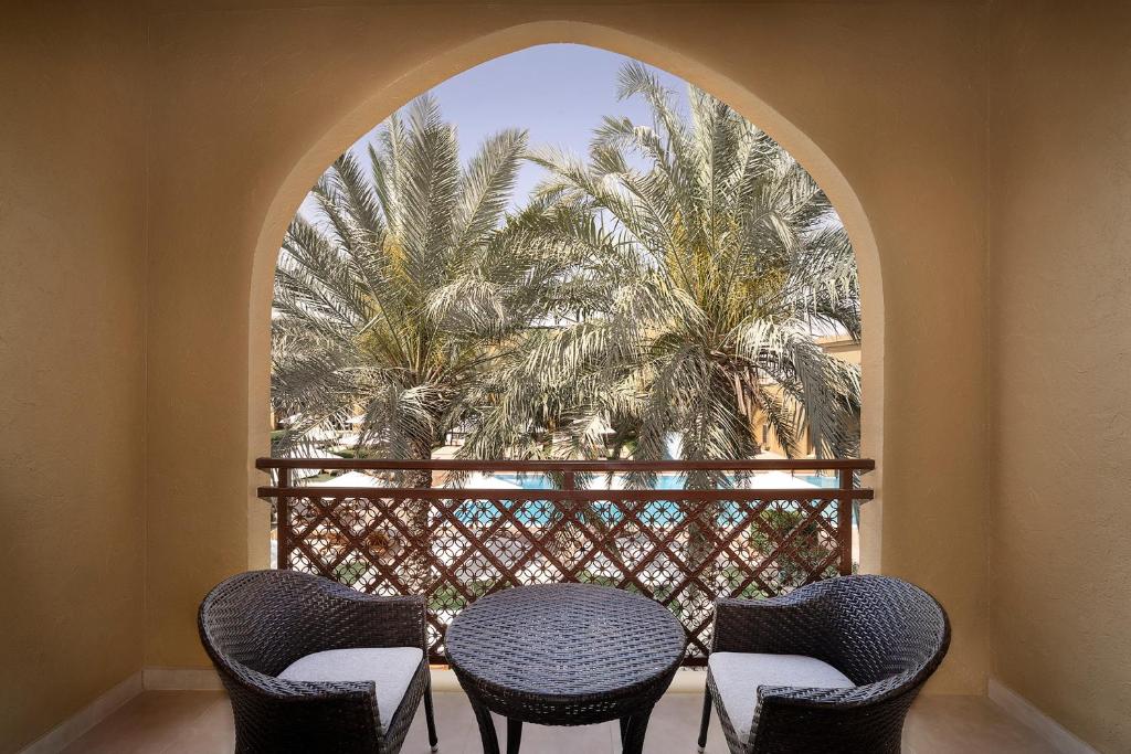 a balcony with a table and chairs and a palm tree at Aldhafra Resort, Vignette Collection by IHG in Madīnat Zāyid