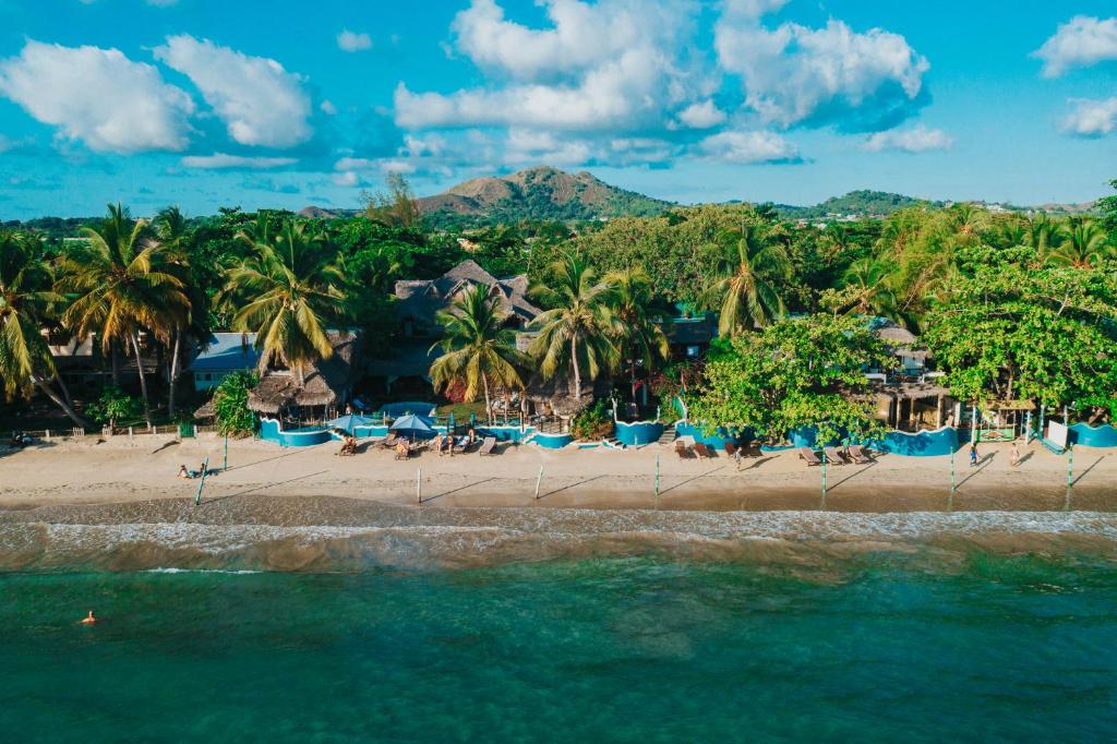 a beach with chairs and palm trees and the ocean at Villa Valiha Boutique Hotel in Madirokely