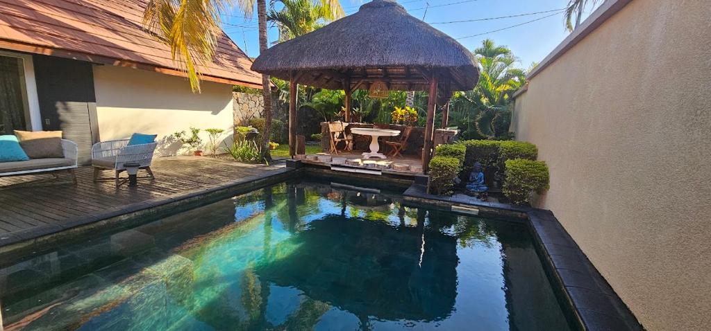 a swimming pool next to a house with a gazebo at Villa 24 in Grand-Baie